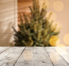 Image of Empty wooden surface and blurred view of Christmas tree in room, space for text. Interior design