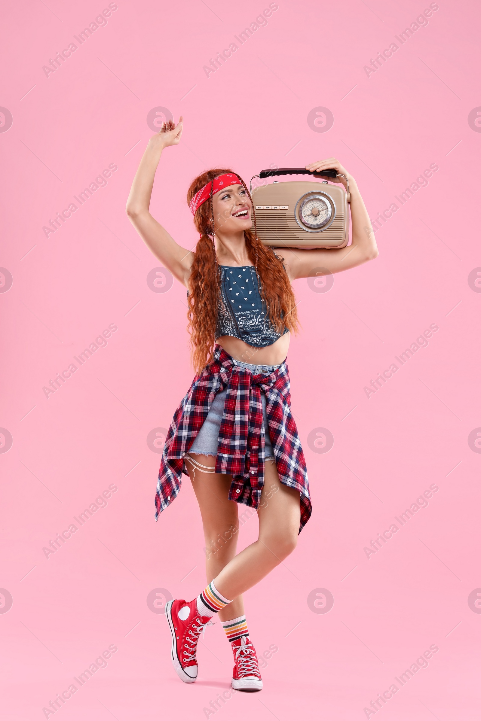 Photo of Stylish young hippie woman with retro radio receiver on pink background