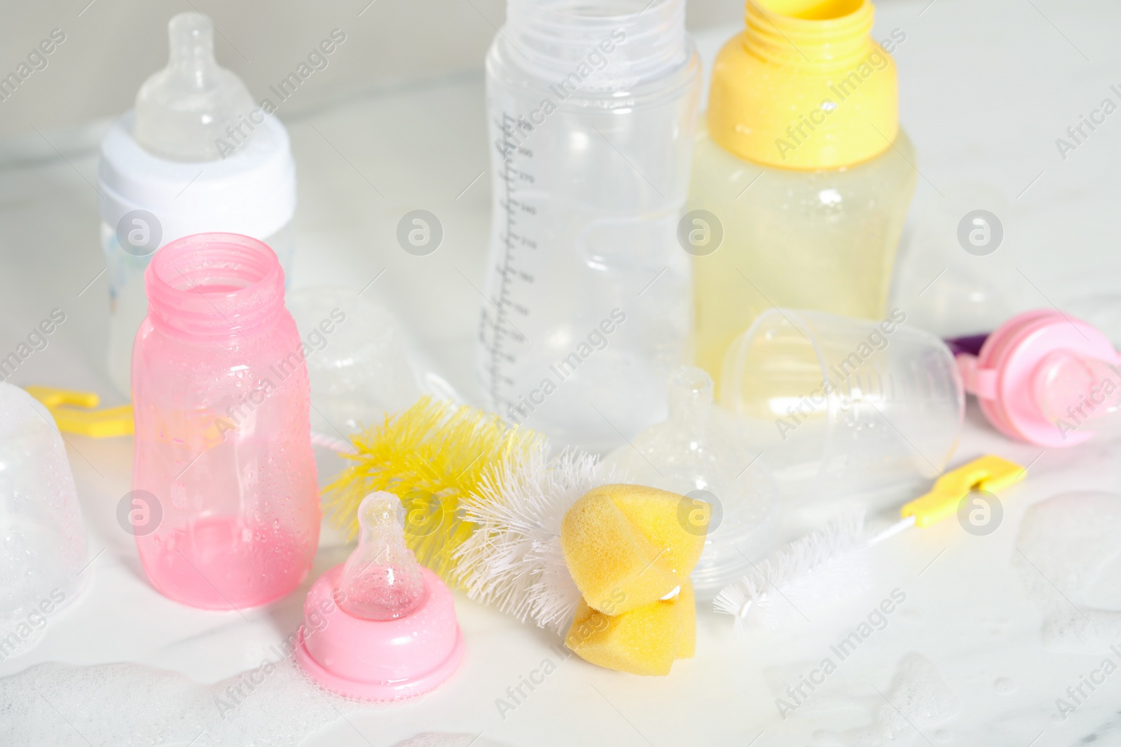 Photo of Clean baby bottles and nipples after sterilization near brushes on white table