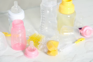 Photo of Clean baby bottles and nipples after sterilization near brushes on white table