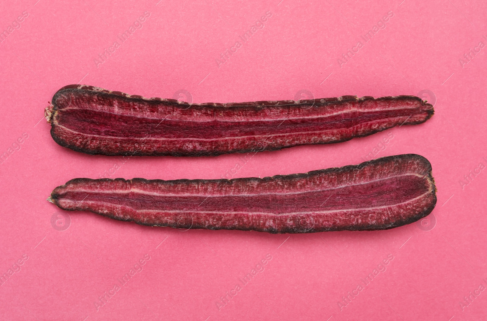 Photo of Halves of raw purple carrot on pink background, flat lay