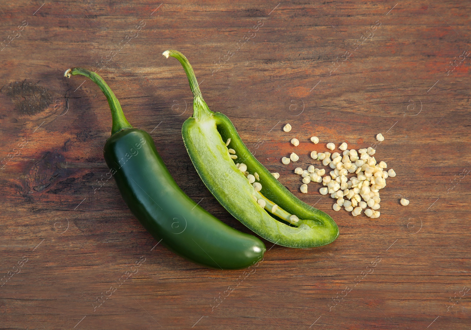 Photo of Fresh green jalapeno peppers and seeds on wooden table, flat lay