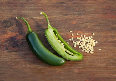 Fresh green jalapeno peppers and seeds on wooden table, flat lay