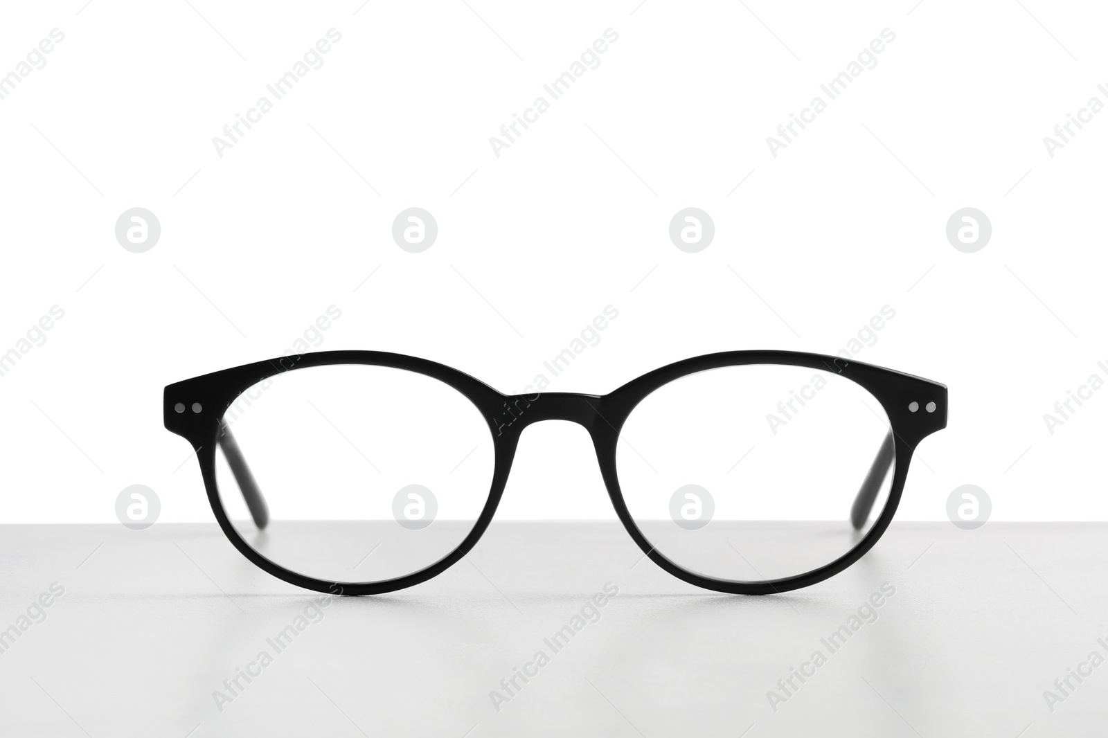 Photo of Stylish glasses with black frame on table against white background