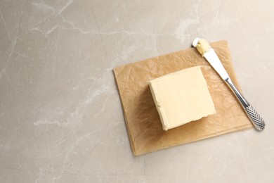 Photo of Block of tasty butter and knife on light table, top view. Space for text