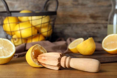 Photo of Composition with fresh lemon half and wooden juicer on table