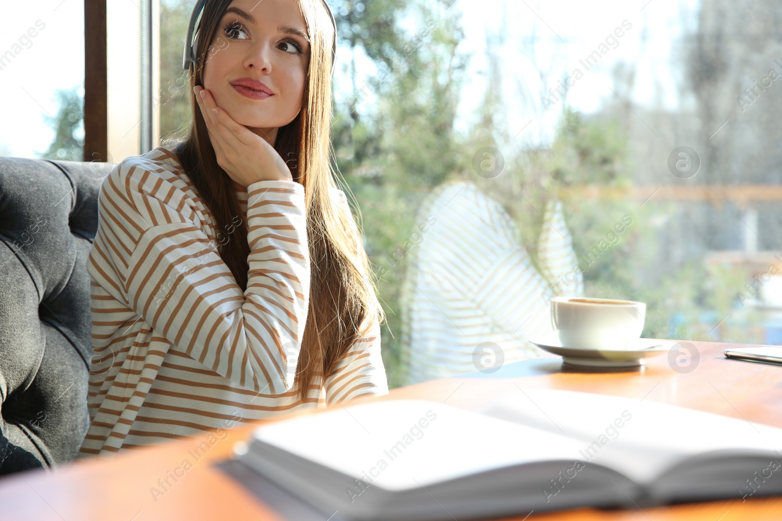 Photo of Woman listening to audiobook at table in cafe