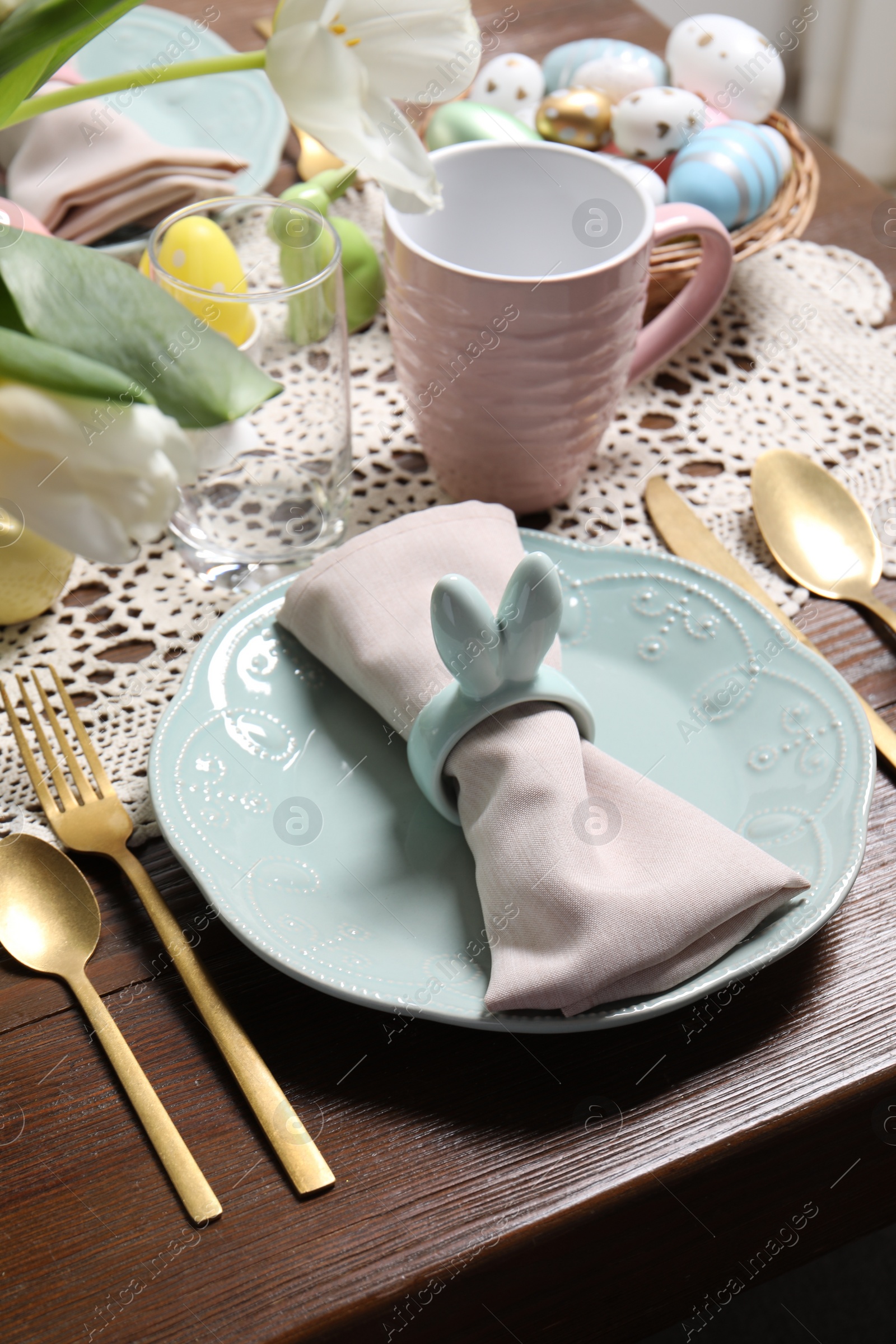 Photo of Festive table setting with napkin ring in shape of bunny ears, closeup. Easter celebration