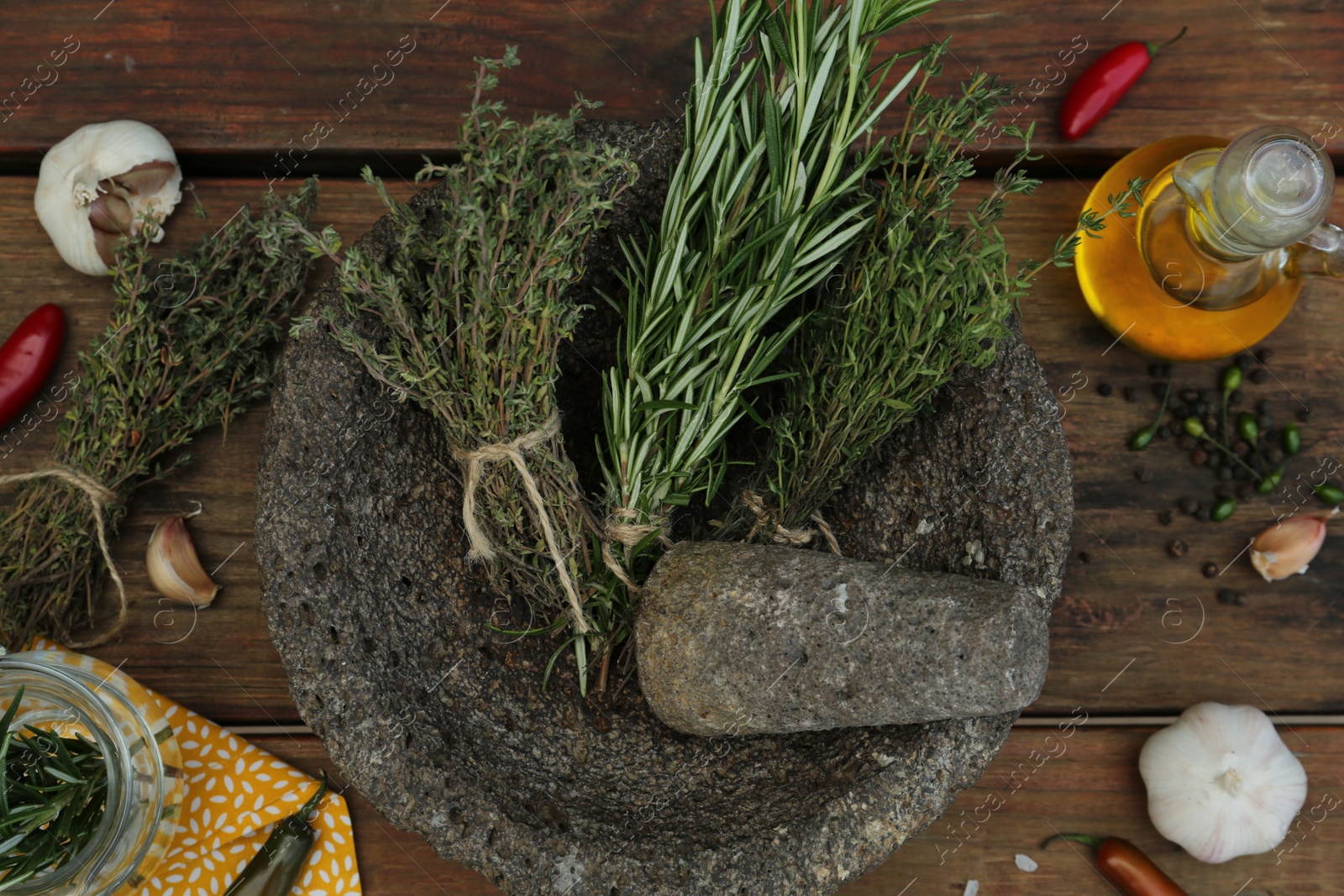 Photo of Mortar, different herbs, vegetables and oil on wooden table, flat lay