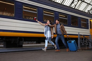 Being late. Worried couple with suitcase running towards train at station