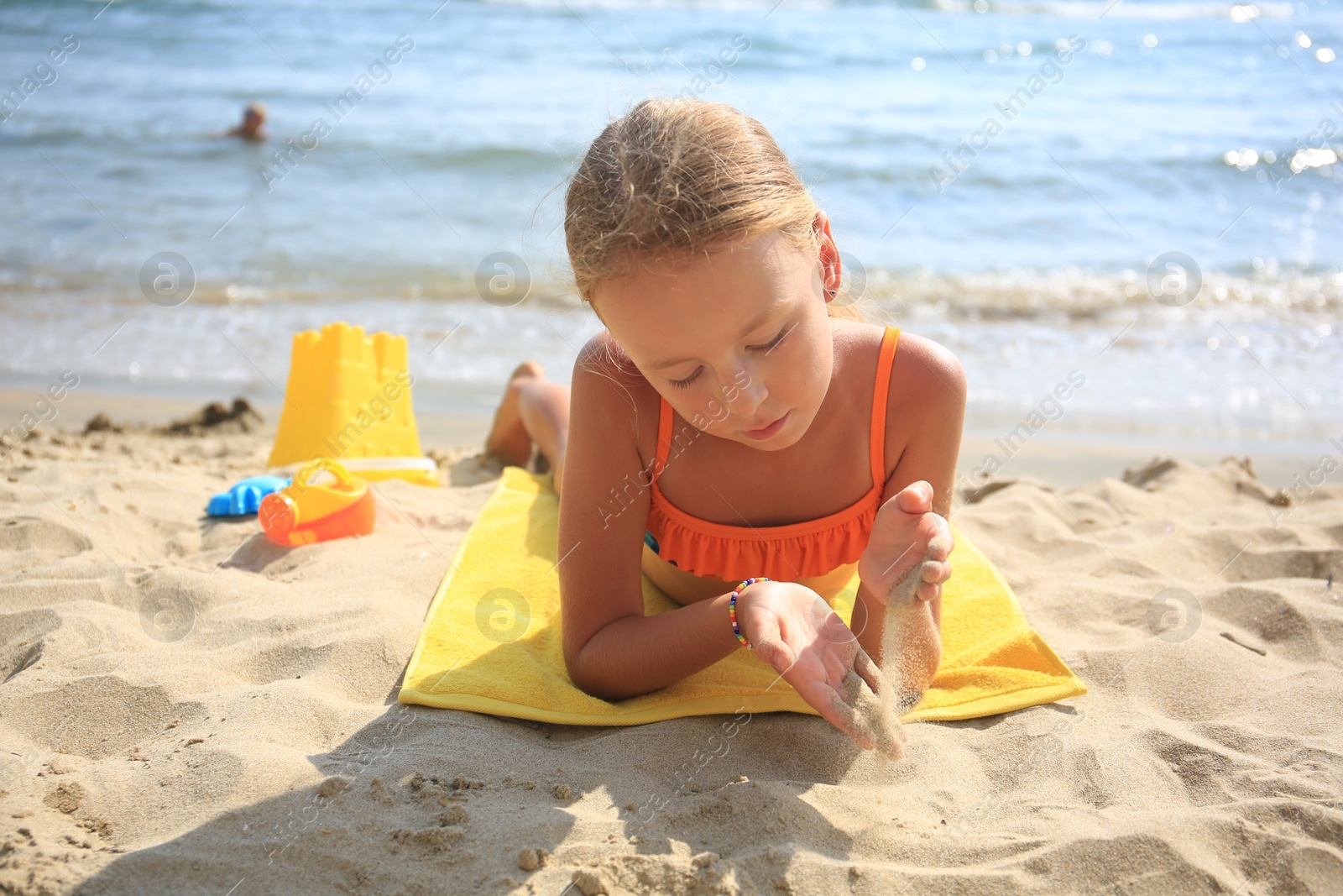 Photo of Little girl playing with sand on beach near sea