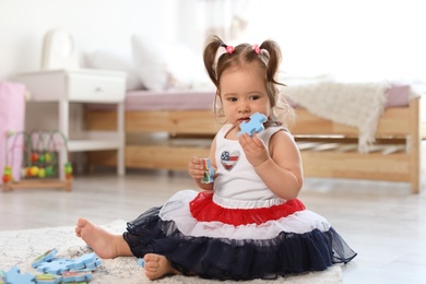 Photo of Adorable little baby girl playing with puzzles on floor in room