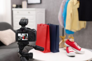 Fashion blogger's workplace. Sneakers, shopping bags and clothes indoors, focus on camera