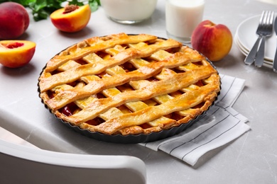 Photo of Delicious peach pie and fresh fruits on light kitchen table