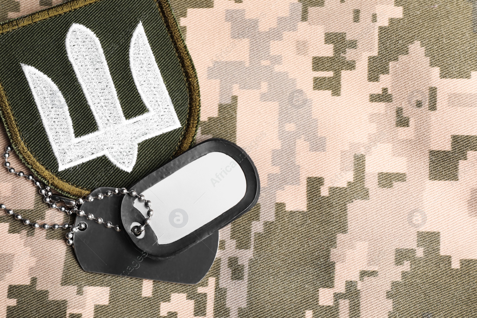 Photo of Military patch and ID tags on pixel Ukrainian camouflage, flat lay. Space for text