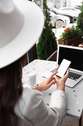 Woman using smartphone in outdoor cafe, closeup