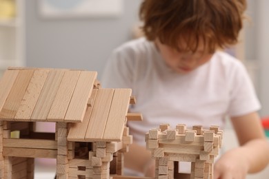 Photo of Little boy playing with wooden entry gate in room, selective focus. Child's toy