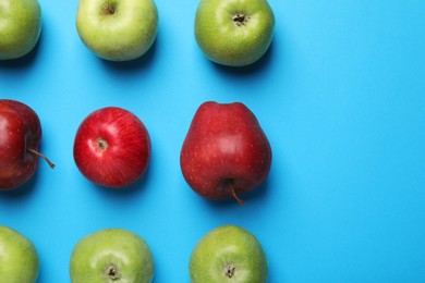 Photo of Ripe red and green apples on light blue background, flat lay. Space for text