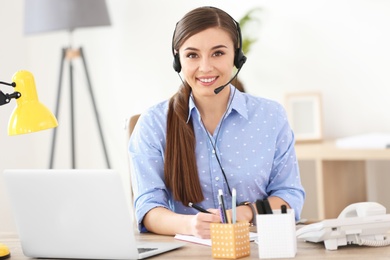 Photo of Young woman talking on phone through headset at workplace