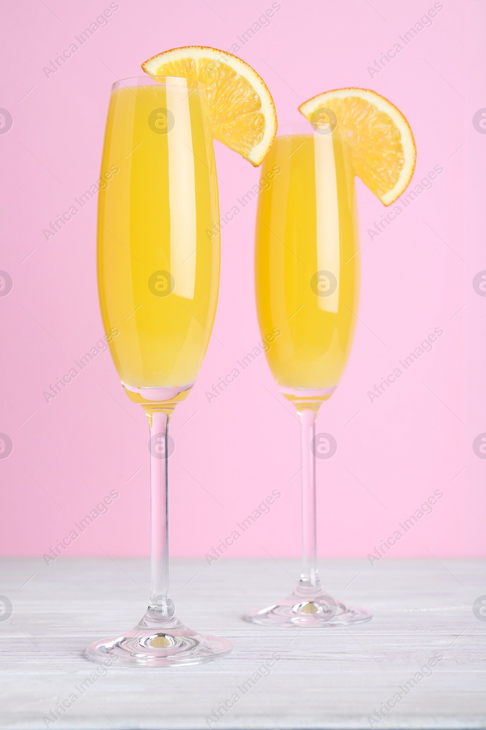 Photo of Fresh alcoholic Mimosa cocktails with orange slices on white wooden table