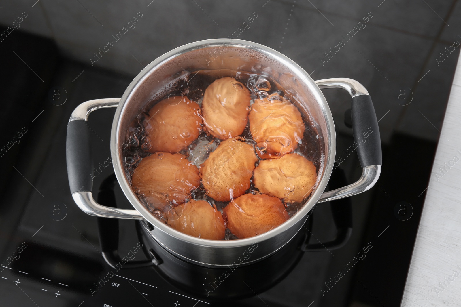 Photo of Chicken eggs boiling in pot on electric stove, above view