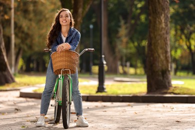 Photo of Young woman with bicycle in park, space for text