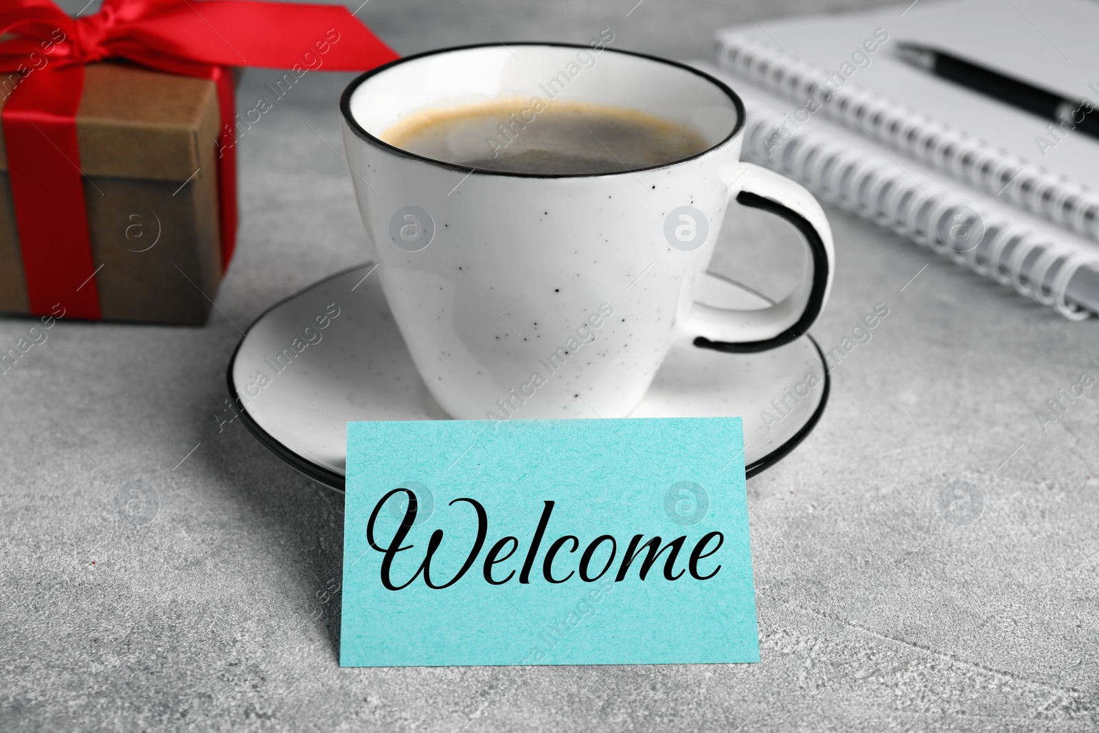 Image of Paper note with word Welcome, cup of coffee and gift box on office desk