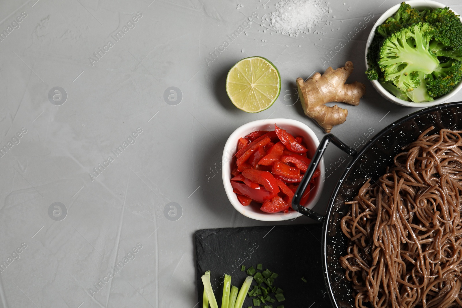 Photo of Wok with noodles and other products on light grey table, flat lay. Space for text