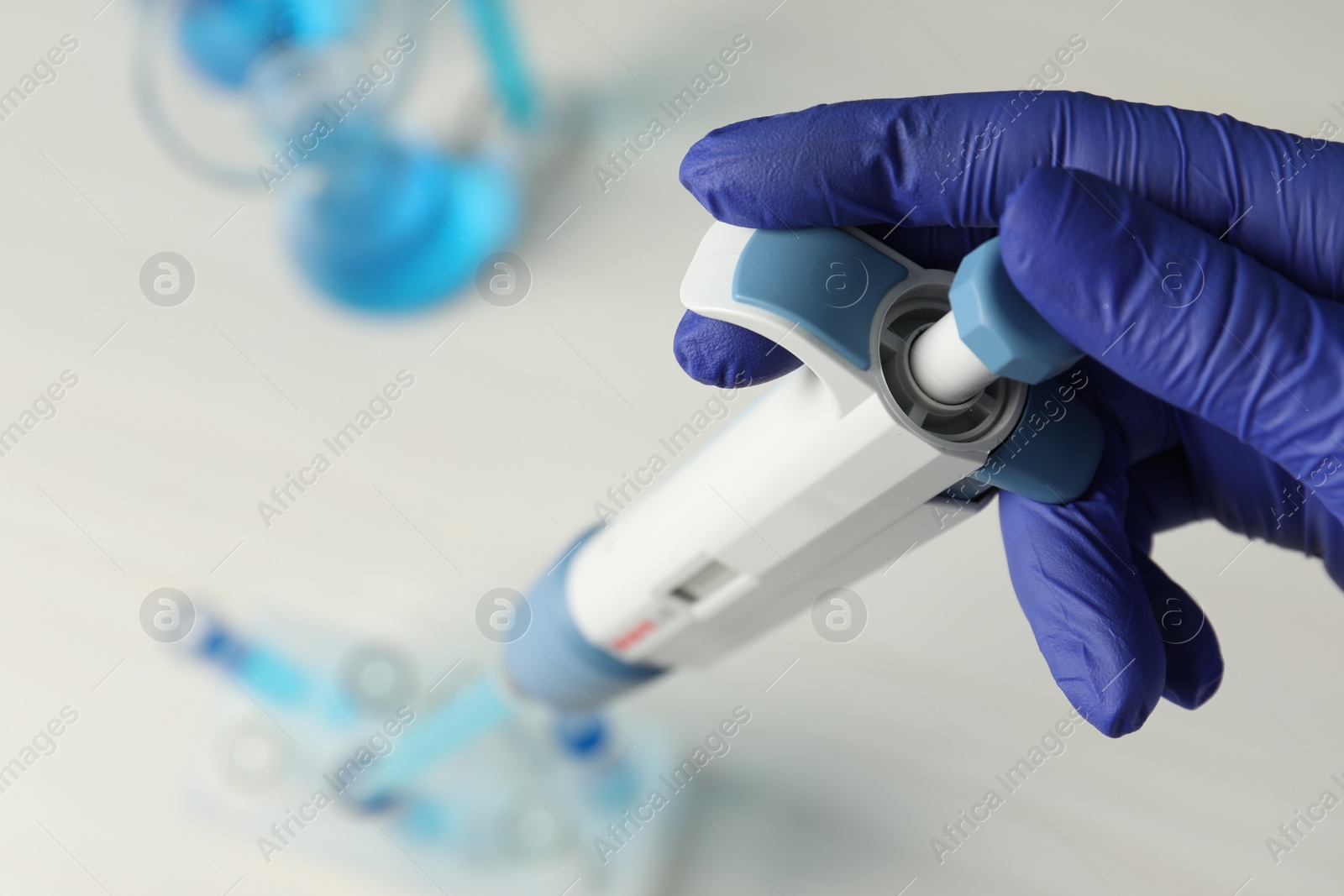 Photo of Laboratory analysis. Scientist dripping sample with micropipette into test tube at table, above view. Space for text