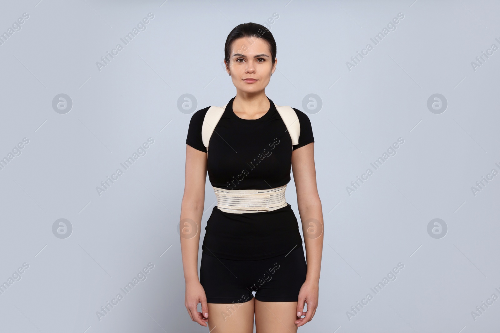 Photo of Beautiful woman with orthopedic corset on grey background