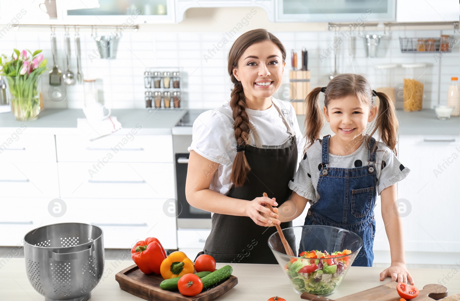 Photo of Young nanny with cute little girl cooking together in kitchen