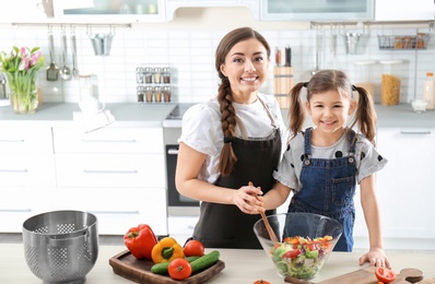 Photo of Young nanny with cute little girl cooking together in kitchen