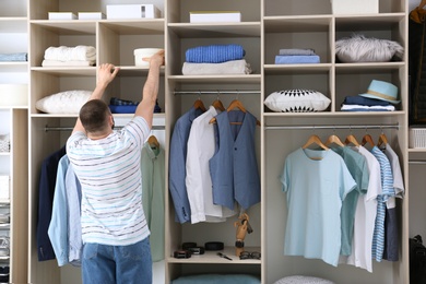 Photo of Man reaching for box on wardrobe shelf