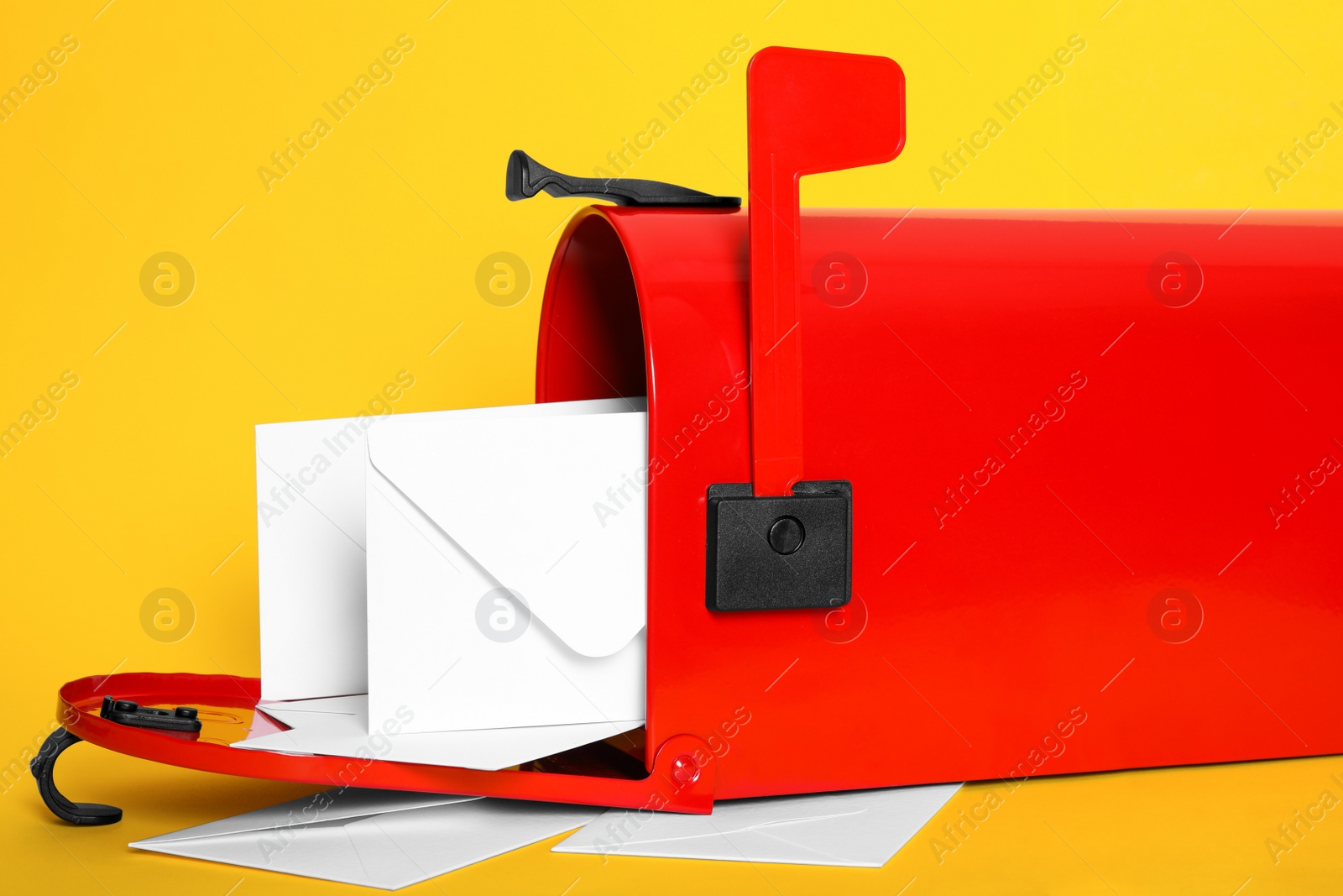 Photo of Open red letter box with envelopes on yellow background, closeup