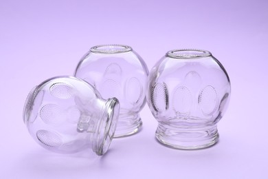 Photo of Glass cups on violet background. Cupping therapy