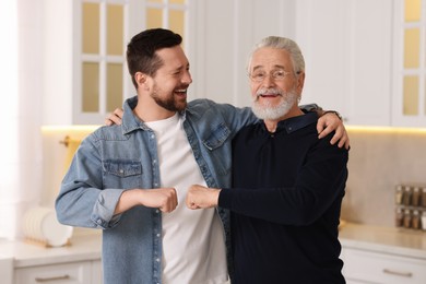 Photo of Happy son and his dad making fist bump at home