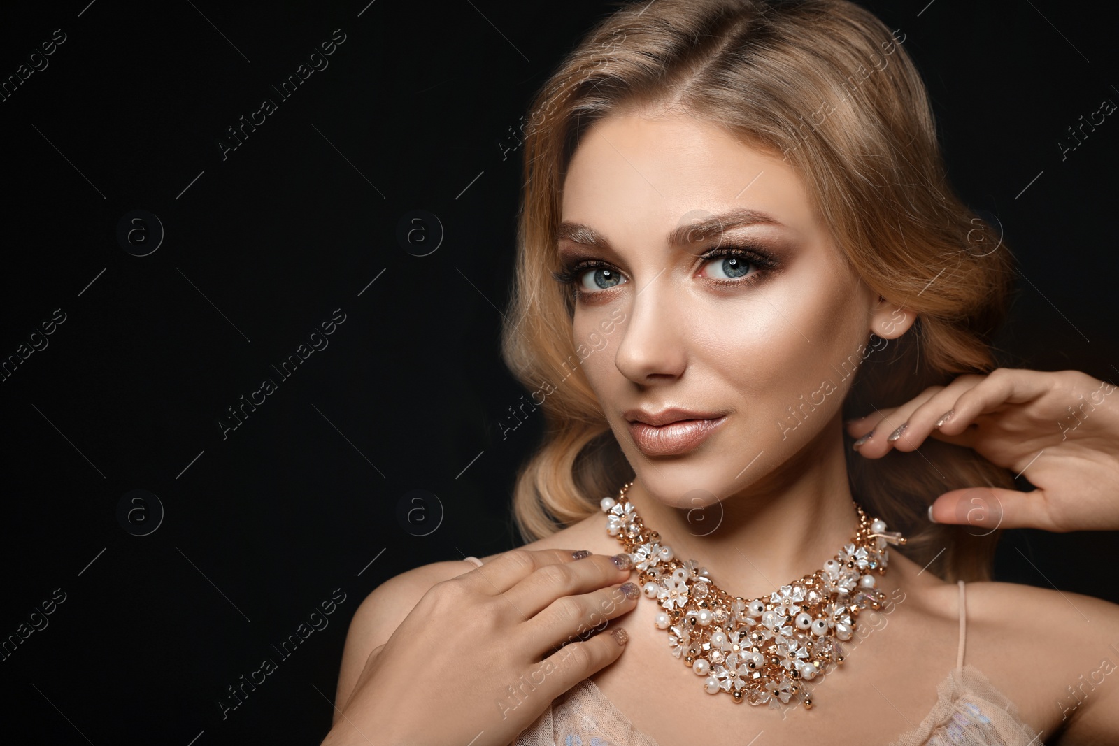 Photo of Beautiful young woman with elegant jewelry on dark background. Space for text