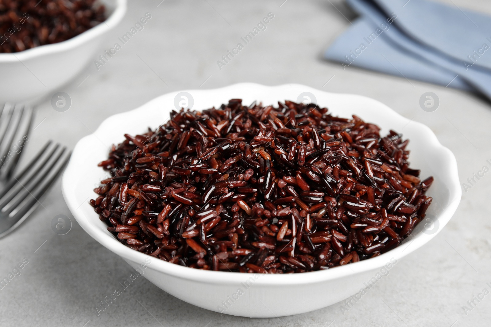 Photo of Bowl with delicious cooked brown rice on white table