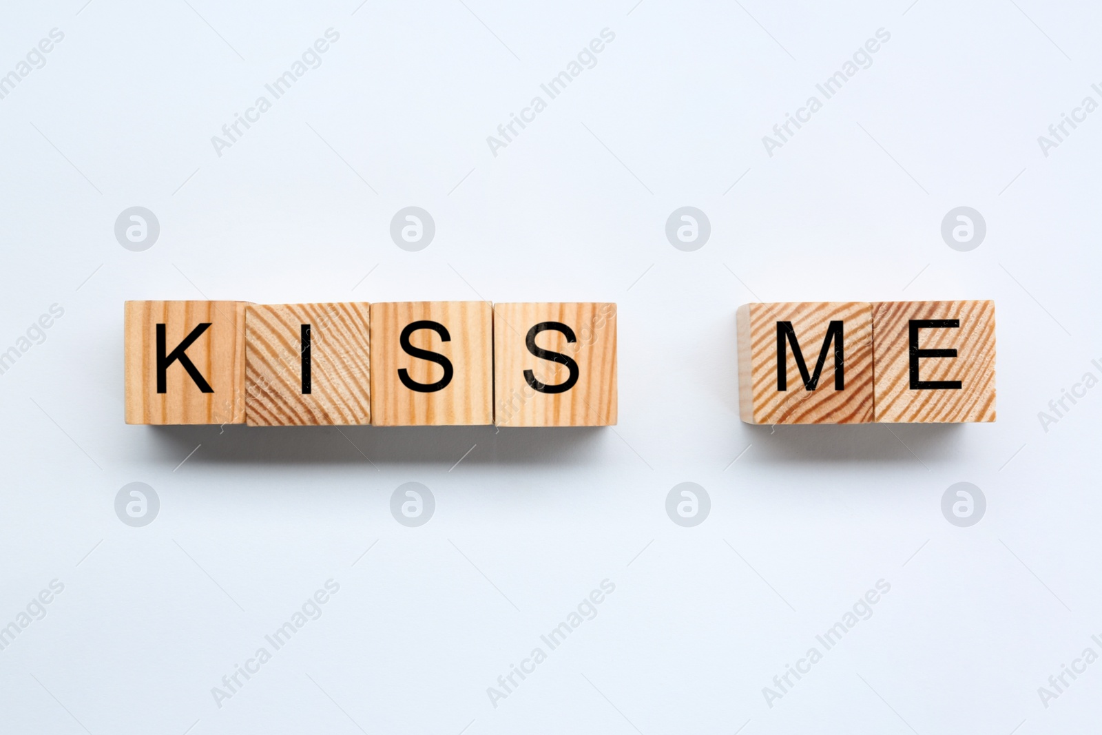 Photo of Wooden cubes with phrase Kiss Me on white background, flat lay