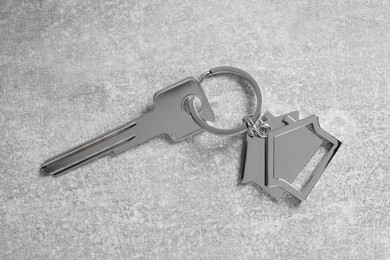 Photo of Key with keychain in shape of house on light grey table, top view