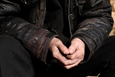 Photo of Poor homeless man with dirty hands outdoors, closeup