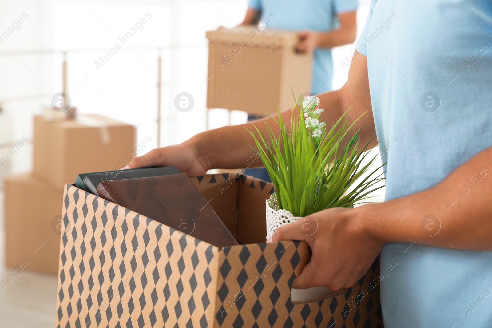 Photo of Professional worker with cardboard box and his colleague in office, closeup. Moving service