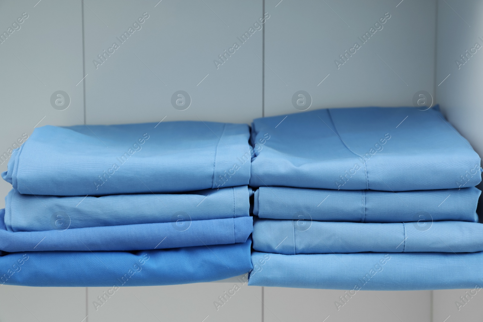 Photo of Light blue medical uniforms on white rack