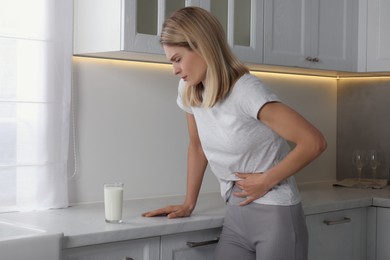 Woman suffering from lactose intolerance in kitchen
