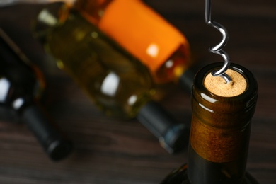 Bottle of wine and corkscrew on blurred background, space for text