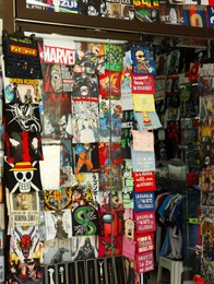 Photo of San Marino, San Marino - August 17, 2022: Different T-shirts, patches, stickers, comics, posters and figures of heroes in shop window