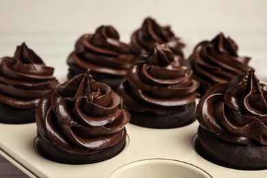 Photo of Delicious chocolate cupcakes with cream in baking tray, closeup