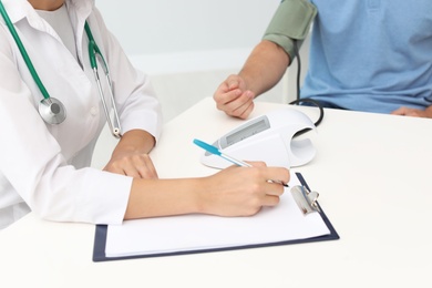 Doctor checking patient's blood pressure in hospital