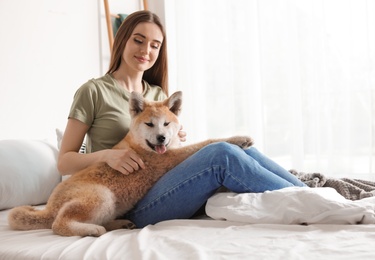 Photo of Young woman with adorable Akita Inu dog in bedroom