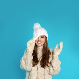 Beautiful young woman in warm clothes on blue background. Winter season